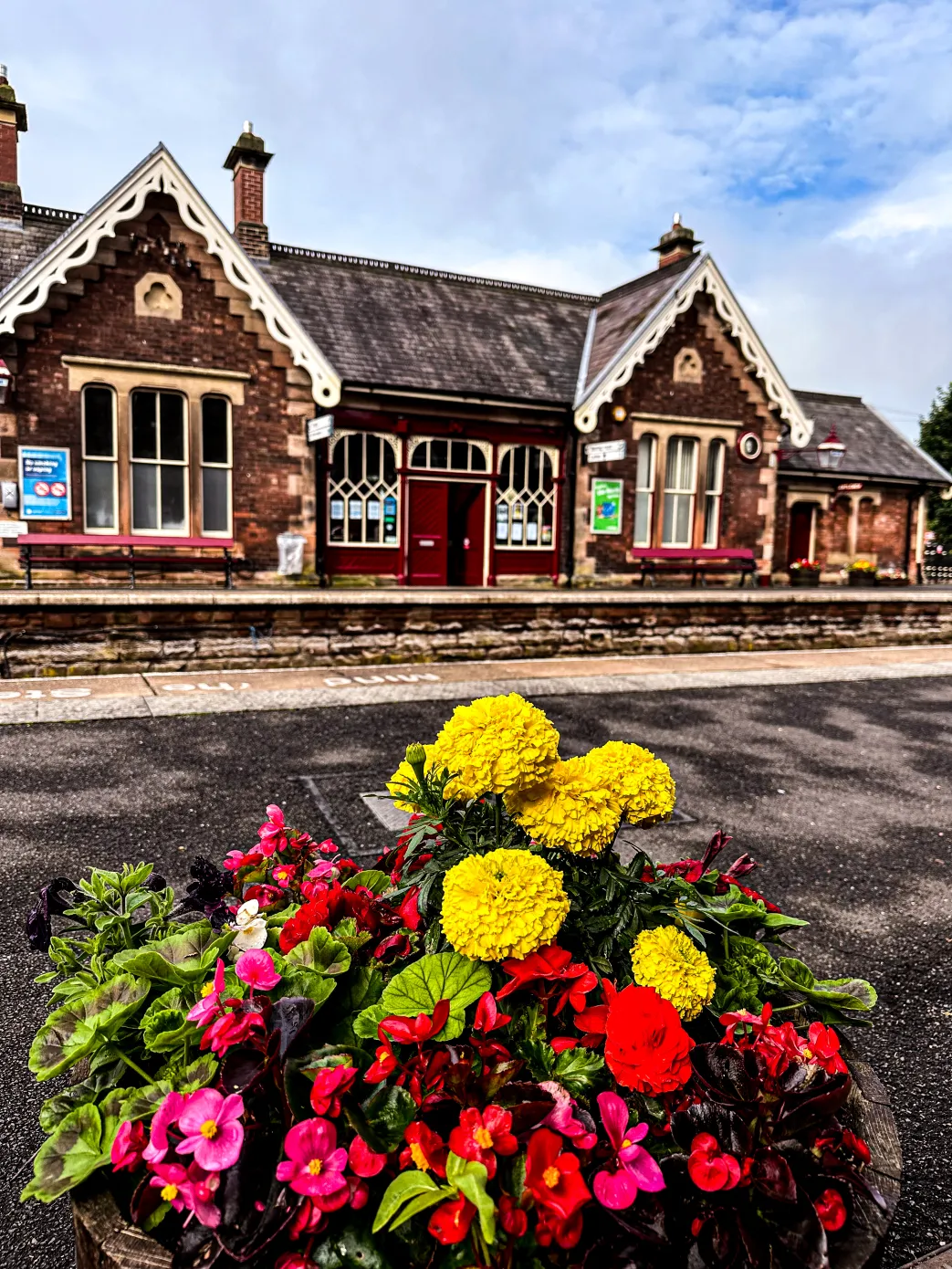 sandstone railway station, with flowers in the forefront. Appleby Railway Station in Cumbria