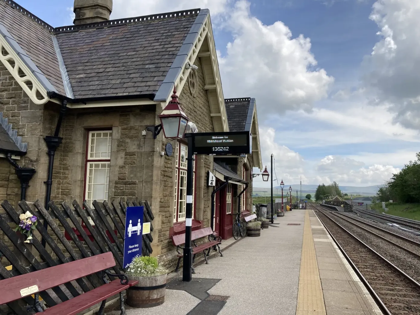 A traditional railway station, with Midland red bench next to a railway line.