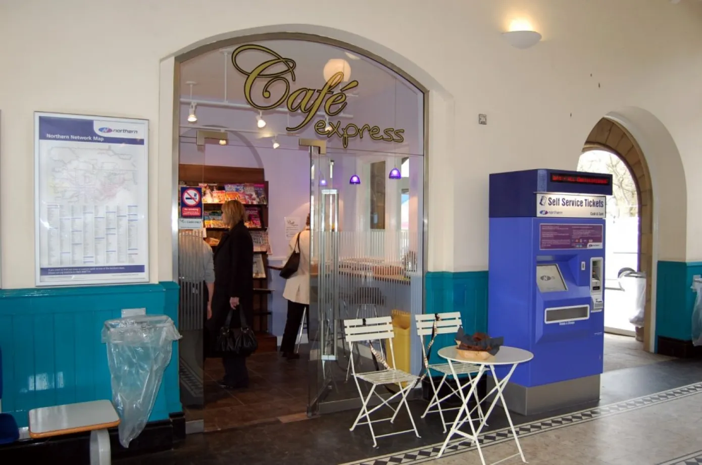 Cafe with two seats outside, next to a ticket machine