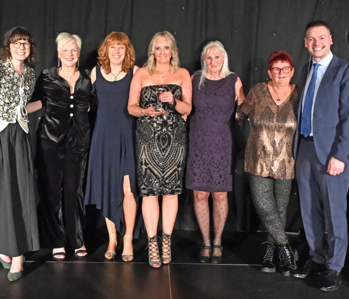 six women and a man on stage presenting an award