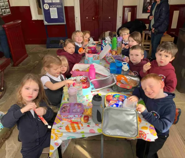 12 school children sit around craft table in Appleby Station
