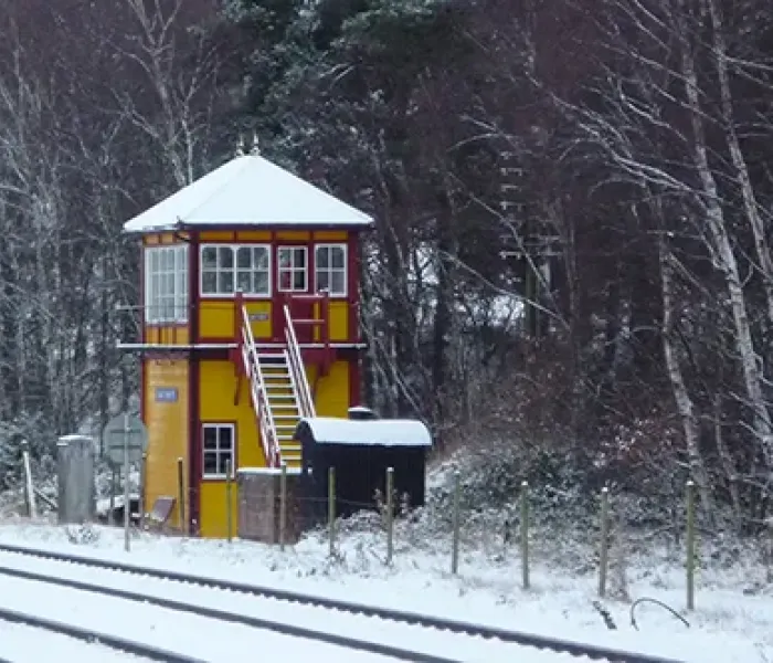 A yellow and red wooden building next to a railway line in the snow.