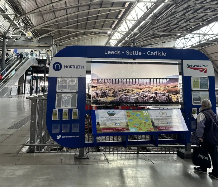 Railway station with a lartge information board and woman looking at the information.