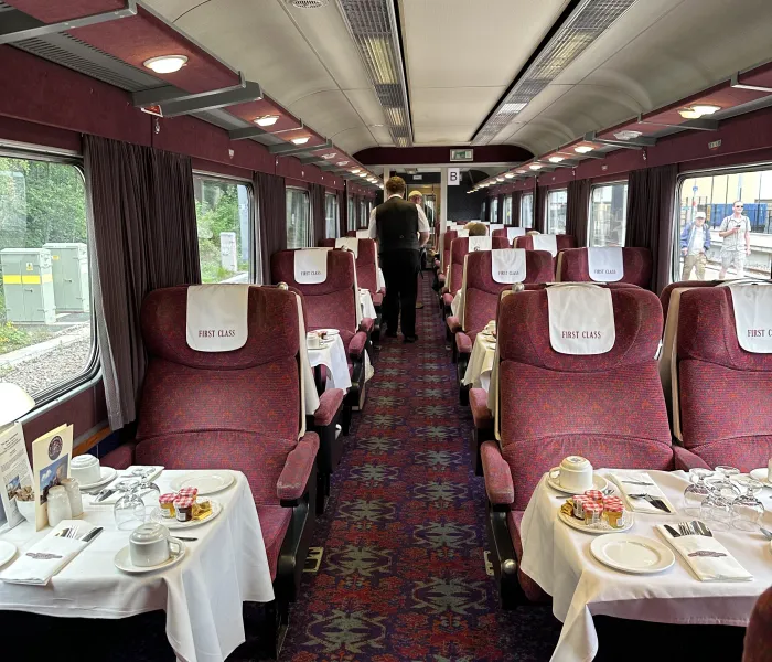 A railway carriage set up for breeakfast with white table cloths.