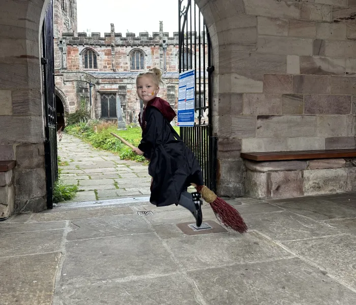 Child on a broomstick, in the cloisters of a church