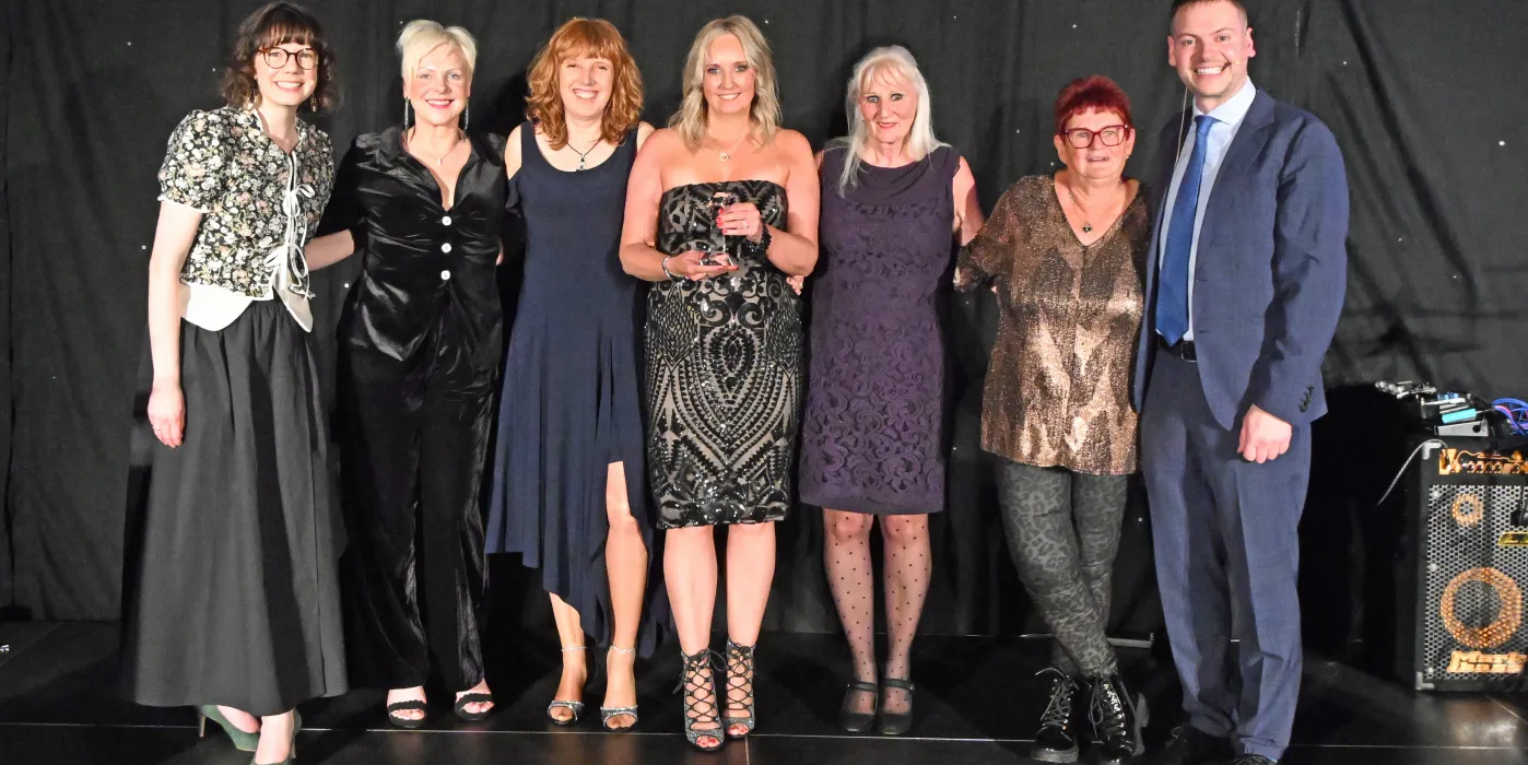 six women and a man on stage presenting an award