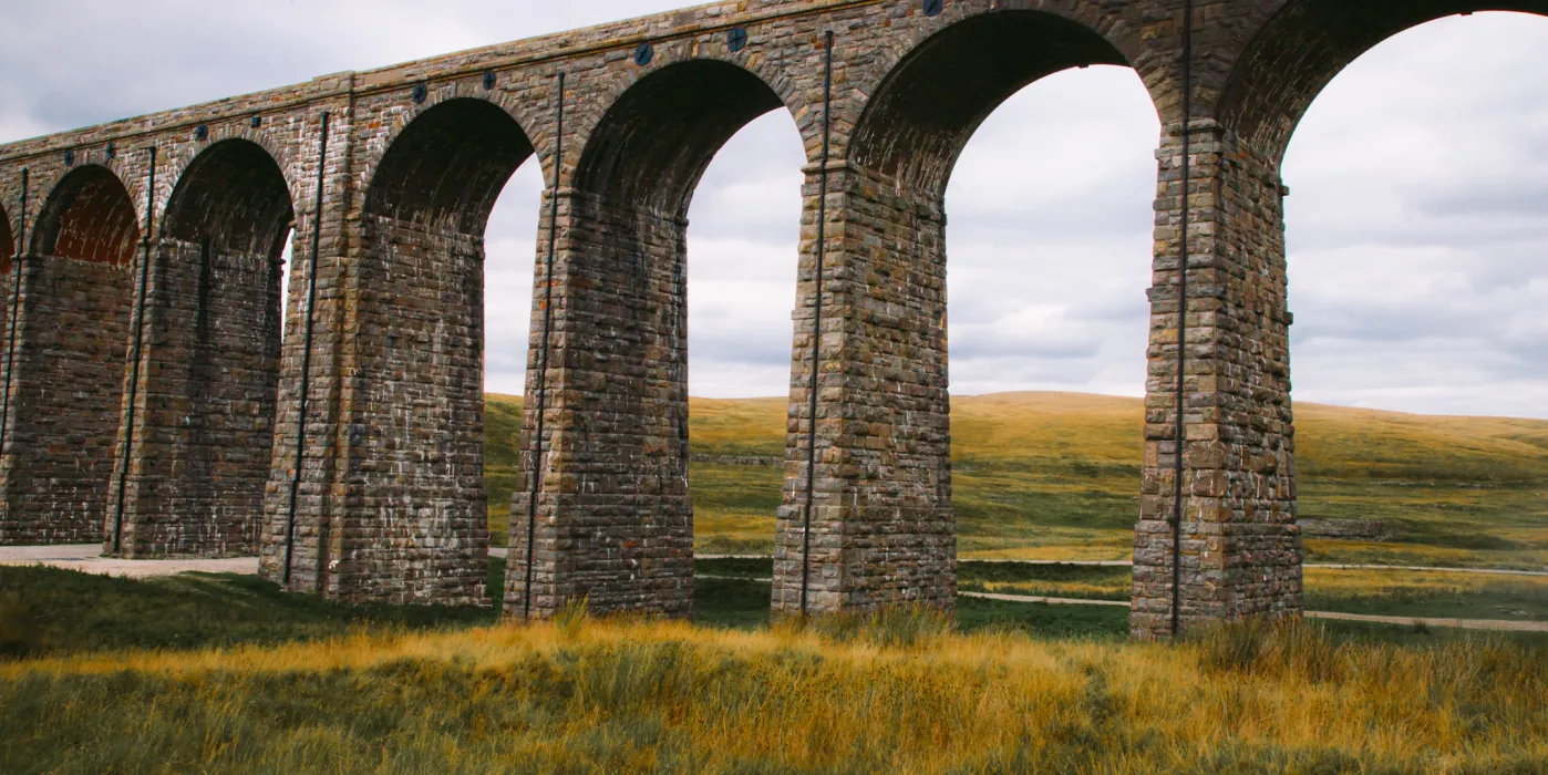 A stone viaduct in a green pasture. Ribblehead viaduct.