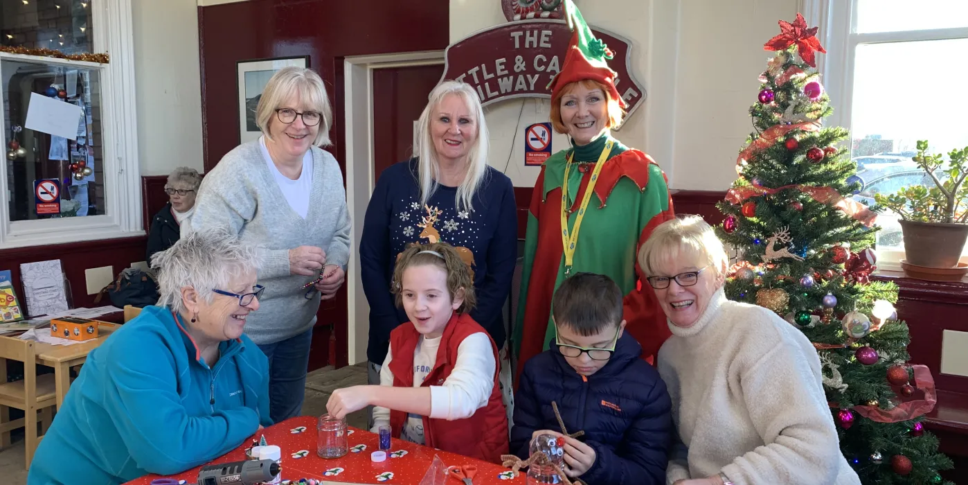 Elf, 4 women and two children making festive crafts