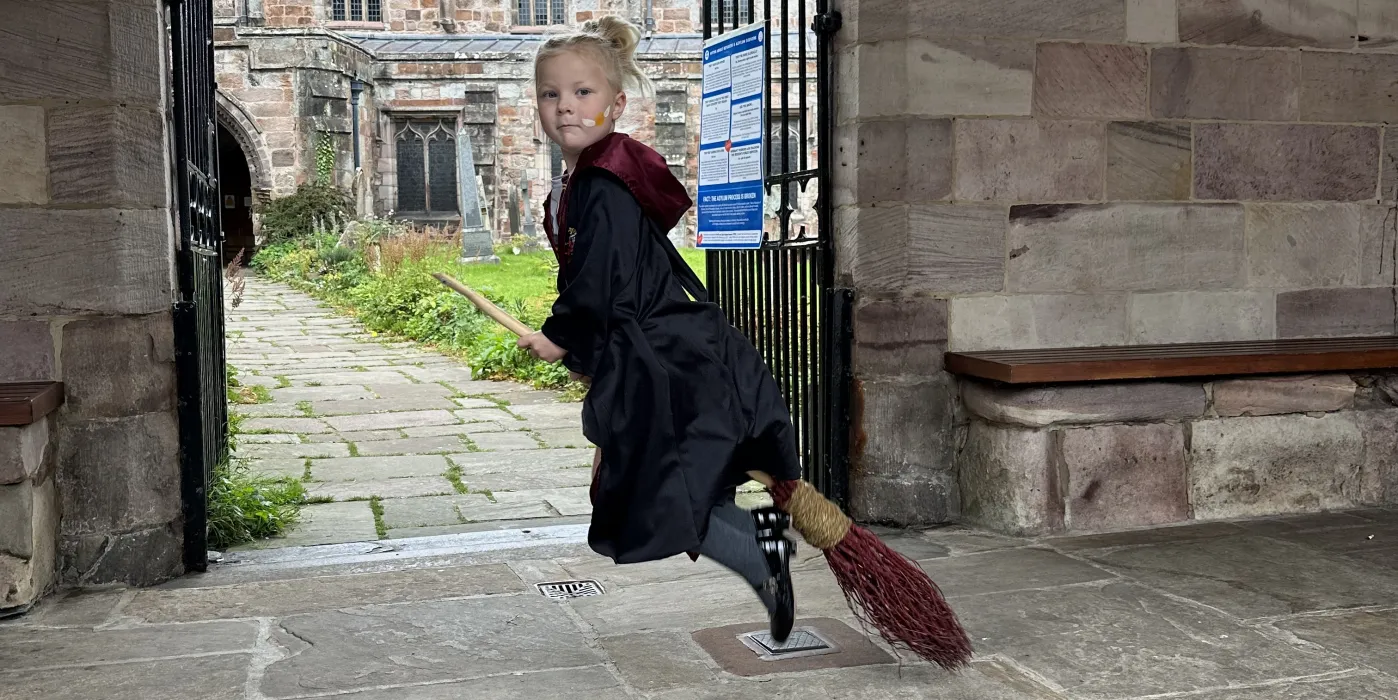 Child on a broomstick, in the cloisters of a church