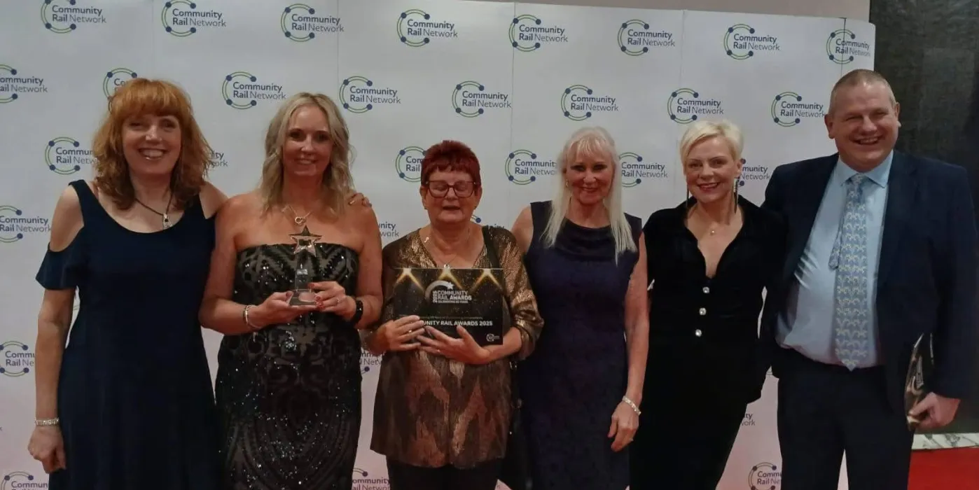 5 woman and one man with an award infrom of banner saying Community Rail Awards 2025